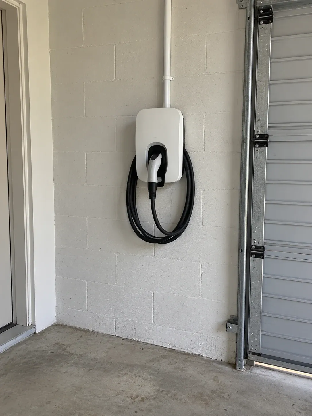 Wall-mounted EV charger with its cable stowed in a garage